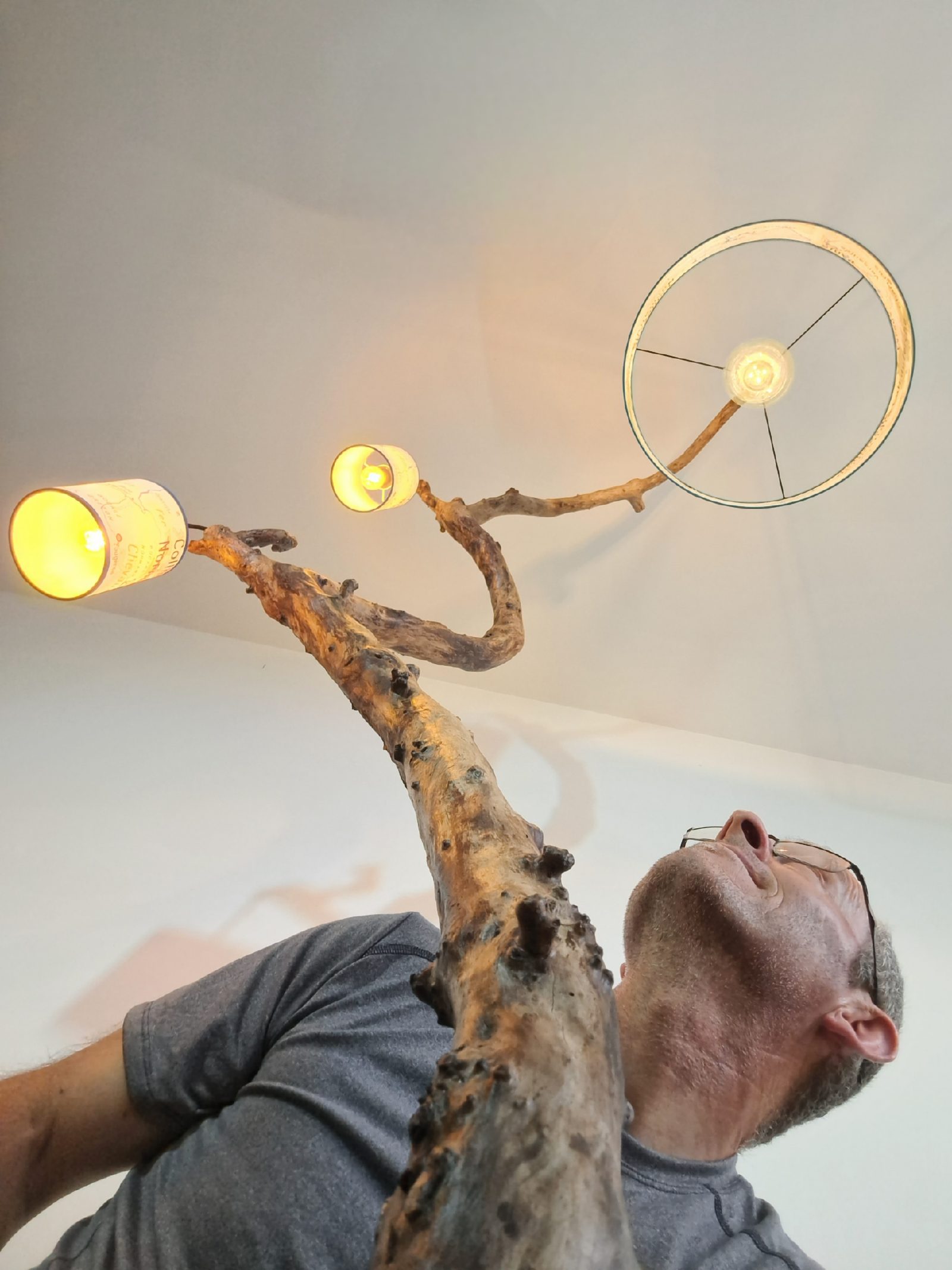 Stéphane Raux admirant l'un de ses luminaires en bois, de jour